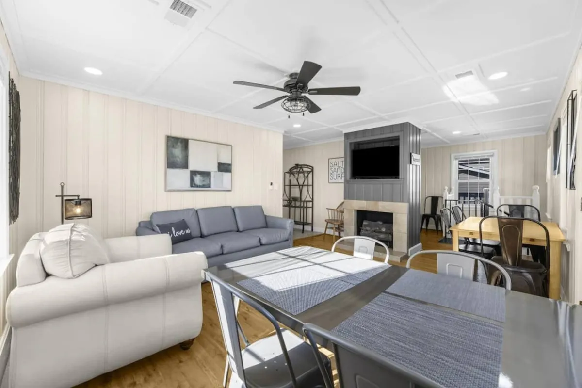A welcoming living area featuring a comfortable sofa, dining table, fireplace, and wall-mounted TV. The setup is ideal for group activities, such as family dinners, game nights, or simply relaxing together.